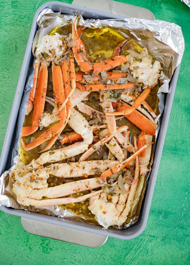 Snow crab legs coated with jerk butter sauce before baking.