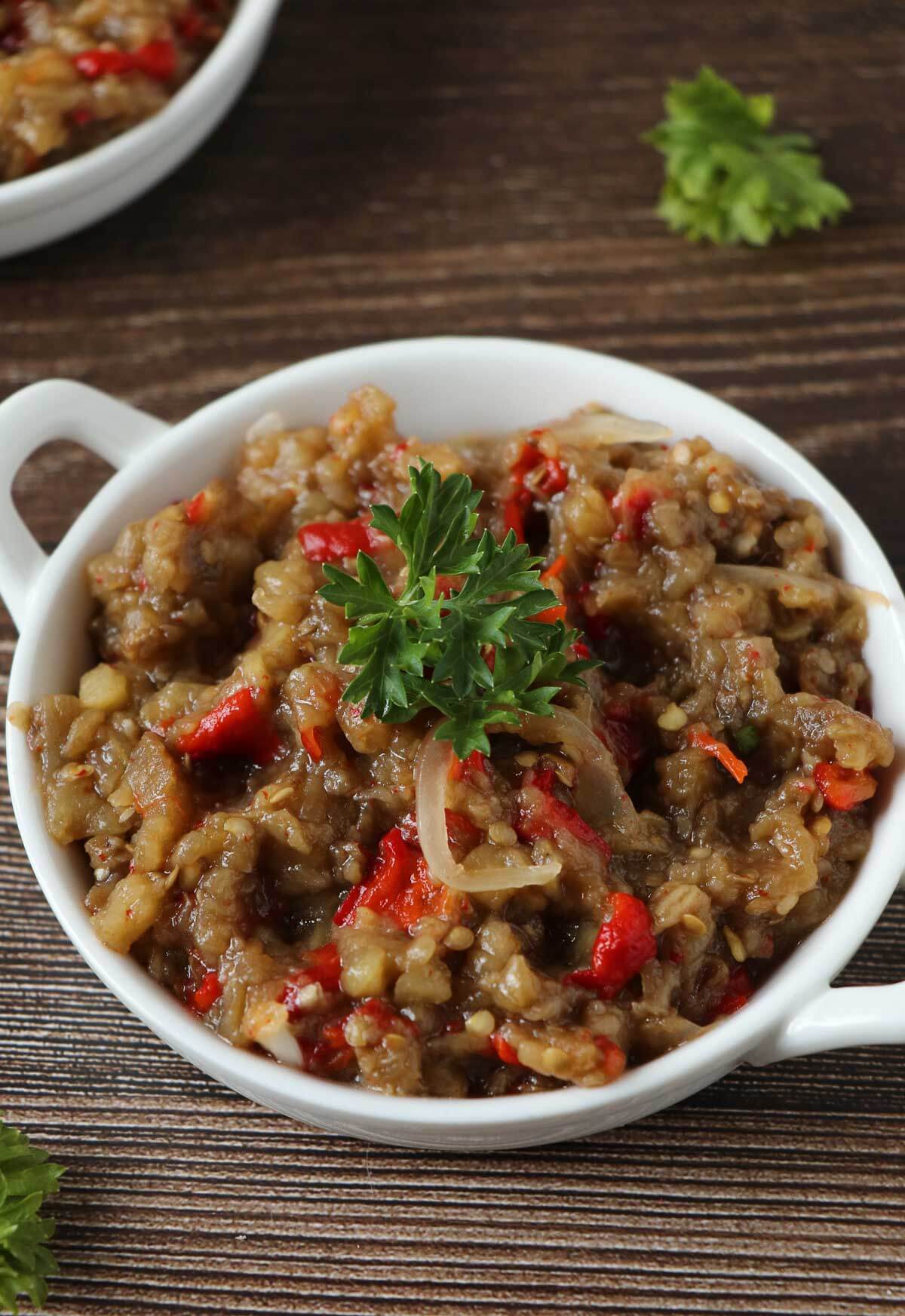 Baigan choka is a Caribbean vegetarian dish that is robustly flavored with garlic and roasted. This mashed treat is best served with roti or rice . Completed choka with a garnish of parsley.