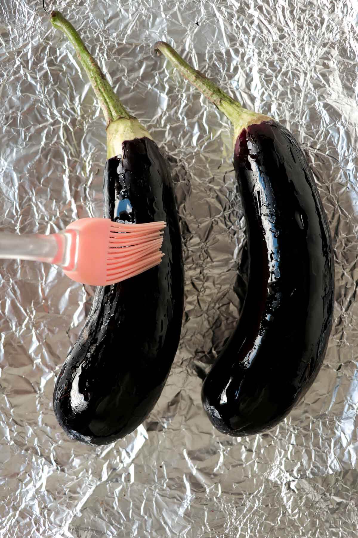 Baigan choka is a Caribbean vegetarian dish that is robustly flavored with garlic and roasted. This mashed treat is best served with roti or rice . Eggplants being coated with coconut oil on foil sheets.