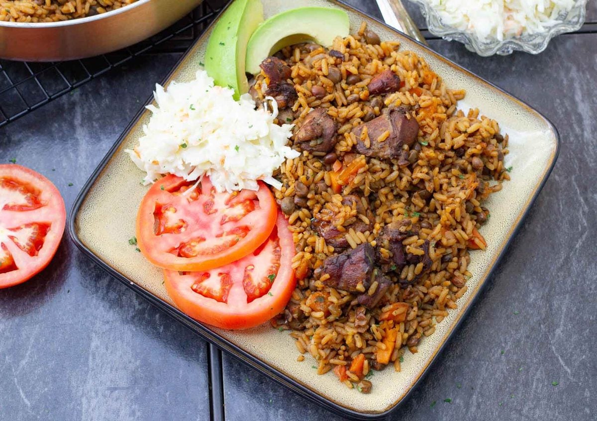 A step by step guide on making the unofficial Trinidad national dish, pelau. A hearty one pot dish of caramelized chicken with rice and pigeon peas. Chicken pelau served with coleslaw, tomatoes, and avocado