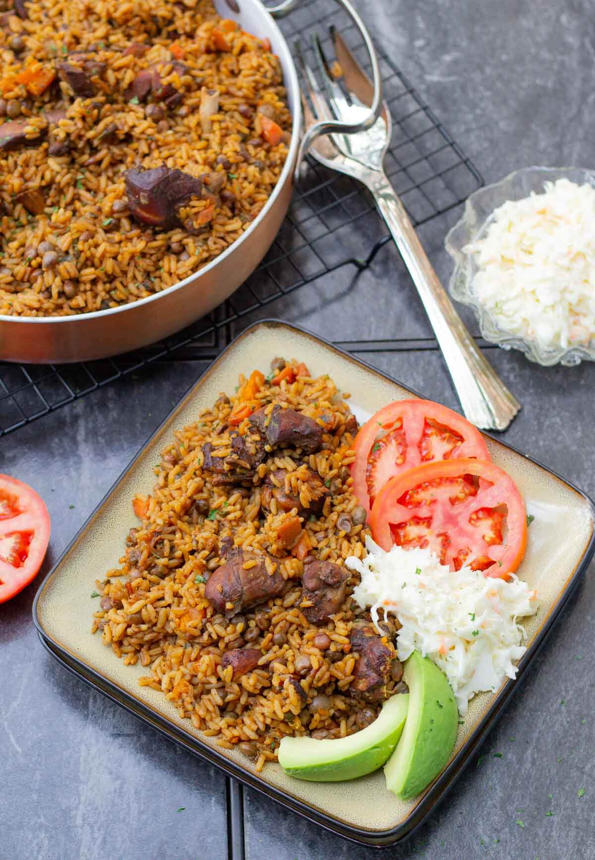 Learn how to make Trinidad’s unofficial national dish, pelau—a hearty one-pot meal with caramelized chicken, rice, and pigeon peas. This step-by-step guide makes it easy! Trinidad chicken pelau served with coleslaw, tomatoes, and avocado