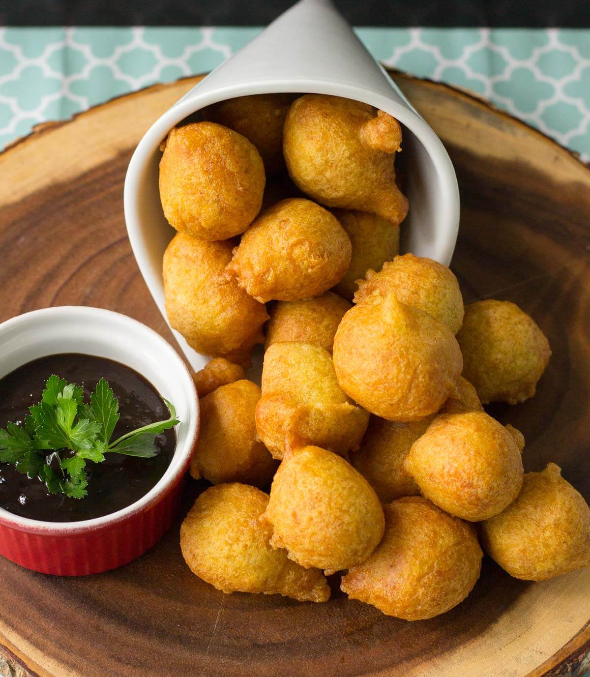 A white container with pholourie with a red bowl with tamarind chutney