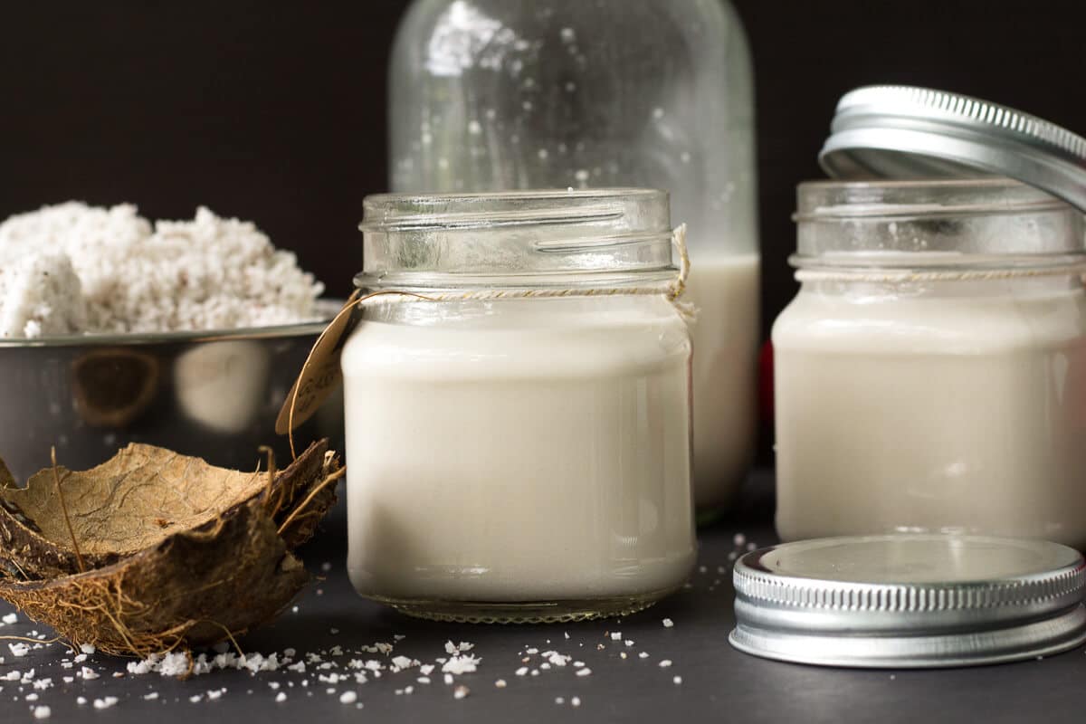 An easy step by step guide for making coconut milk from a fresh dry coconut just like we do it in the Caribbean. Homemade coconut milk poured into a glass bottle with fresh coconut nearby