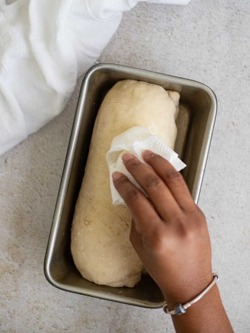 Brushing egg wash over dough before baking Jamaican hard dough bread.