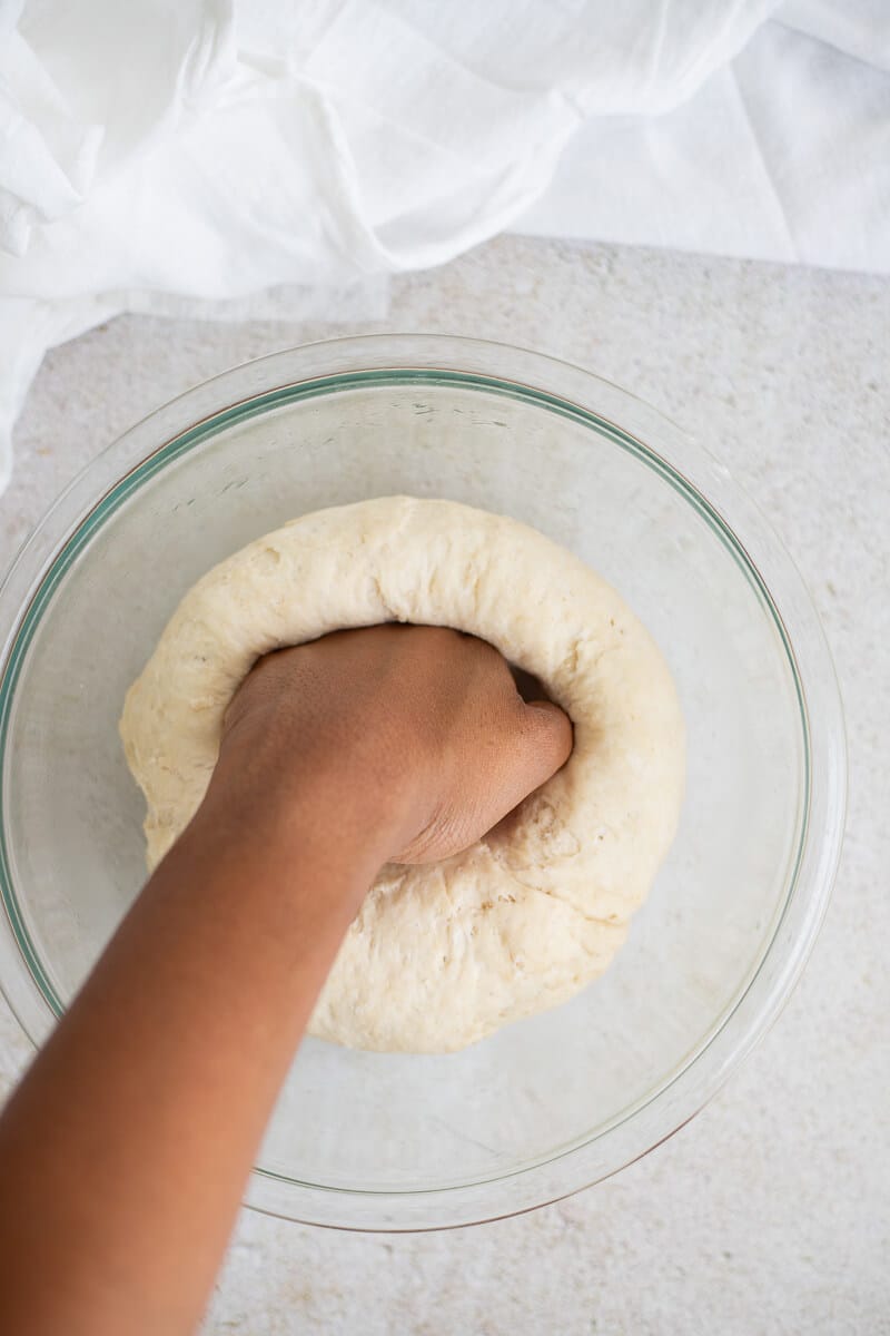 Punching down risen dough before shaping Jamaican hard dough bread.