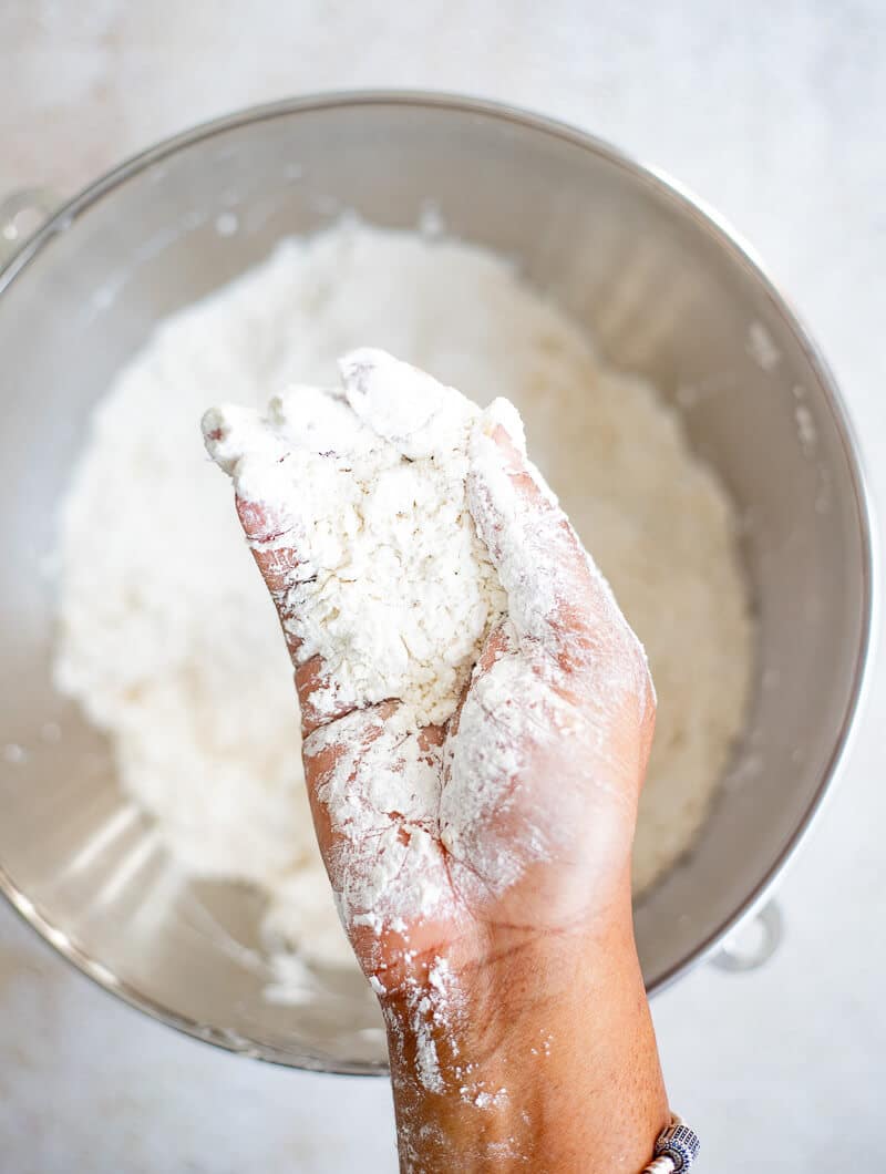 Butter being rubbed into flour mixture while preparing bread dough.