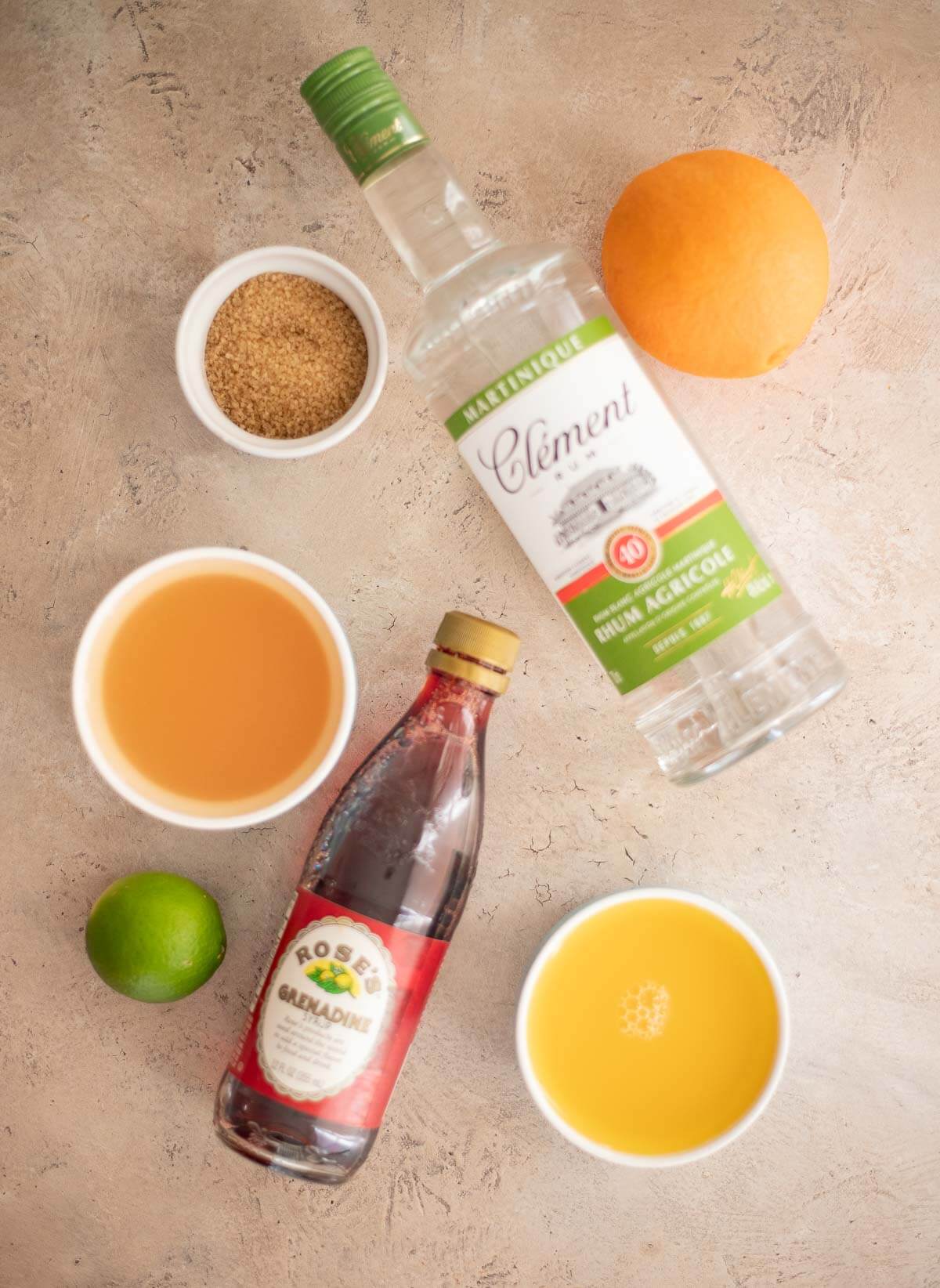 Ingredients for Le Planteur cocktail, including rhum agricole, orange juice, guava juice, Demerara sugar, and grenadine.