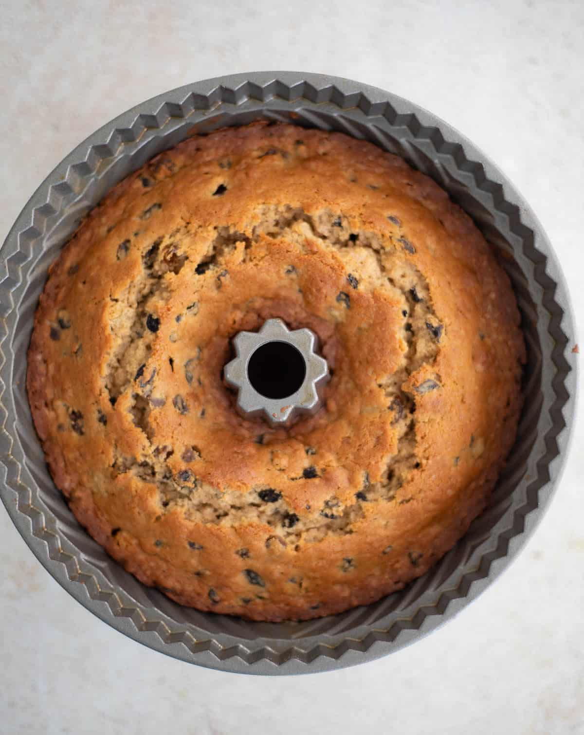Golden-brown fruit sponge cake freshly baked in a Bundt pan, showing its risen surface.