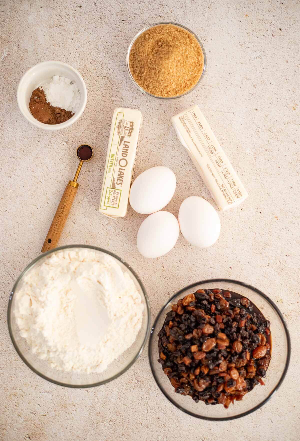 Ingredients for Caribbean fruit sponge cake, including dried fruits, rum, butter, brown sugar, eggs, flour, and spices.