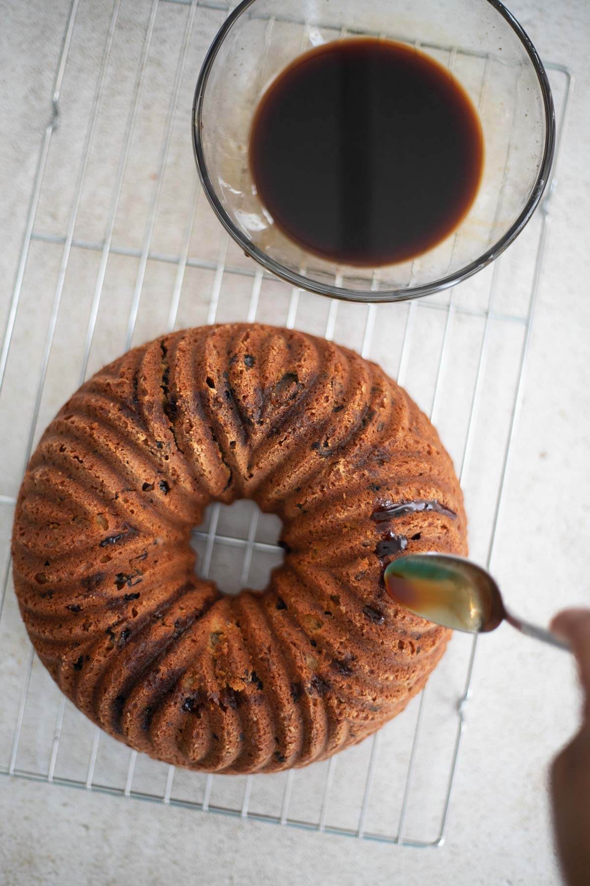 A light sponge cake with fruits soaked in Don Q Anejo. A delicious cake perfect for the Christmas season. #homemadezagat #Exceptional #DonQRum #ad Rum being poured over a freshly baked Caribbean fruit sponge cake on a wire cooling rack.