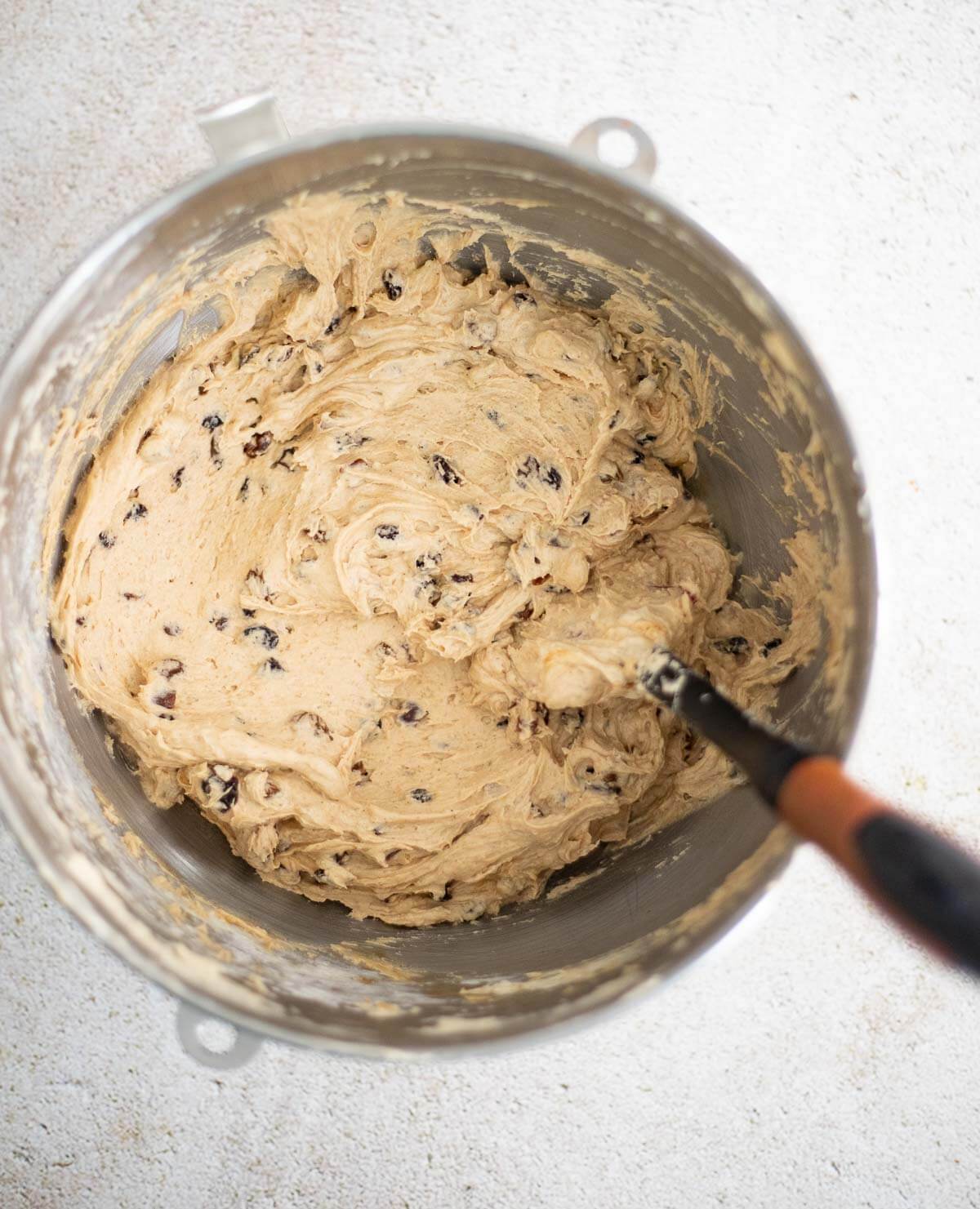 Rum-soaked dried fruits folded into fruit sponge cake batter in a mixing bowl.