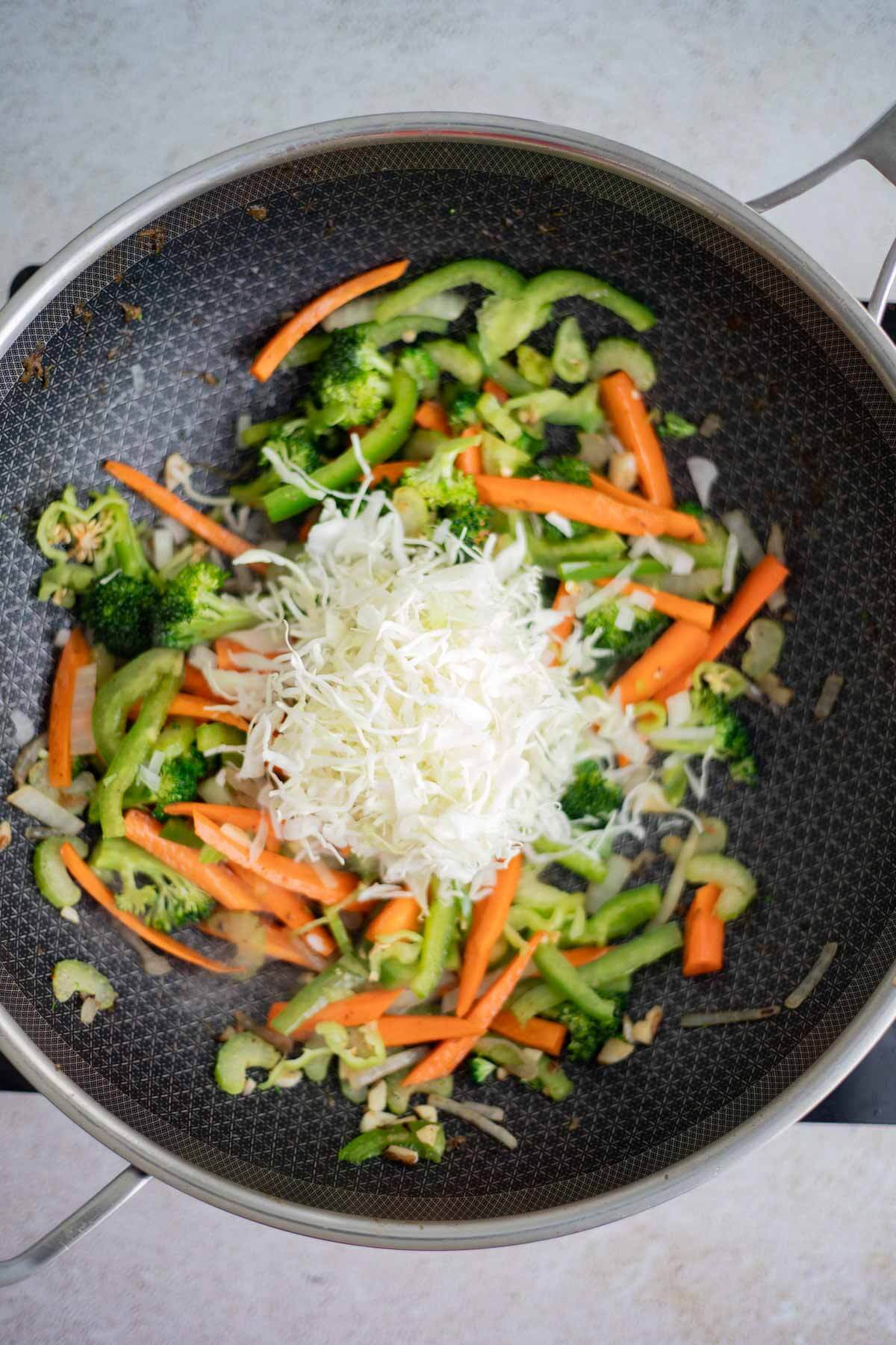 Shredded cabbage added to stir-fried vegetables for chow mein