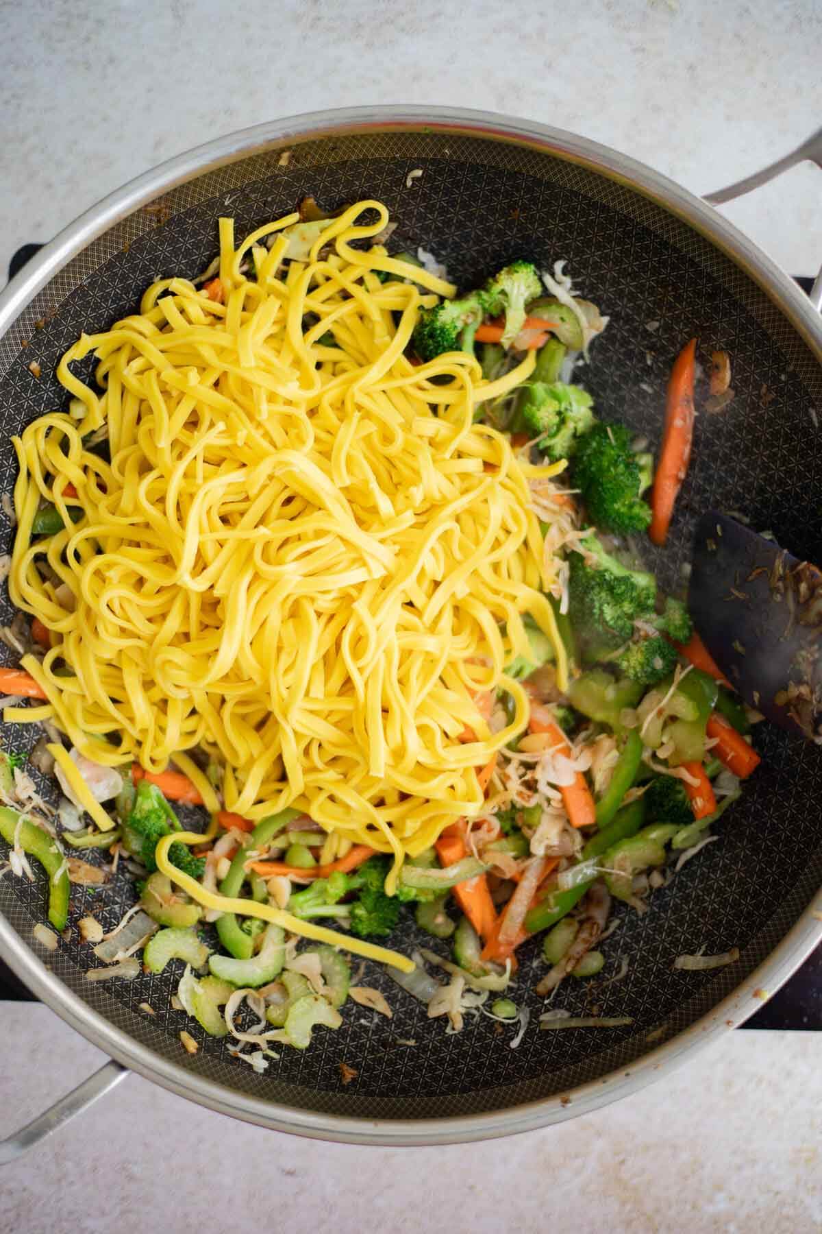 Cooked chow mein noodles added to the stir-fried vegetables