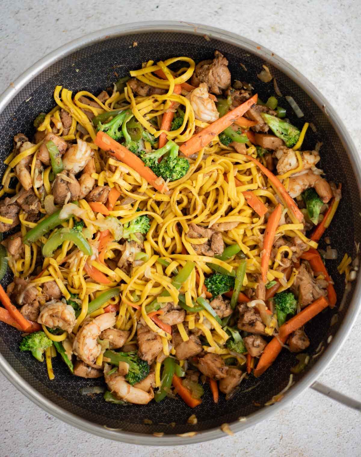 Caribbean chow mein with chicken, shrimp and vegetables in a pan