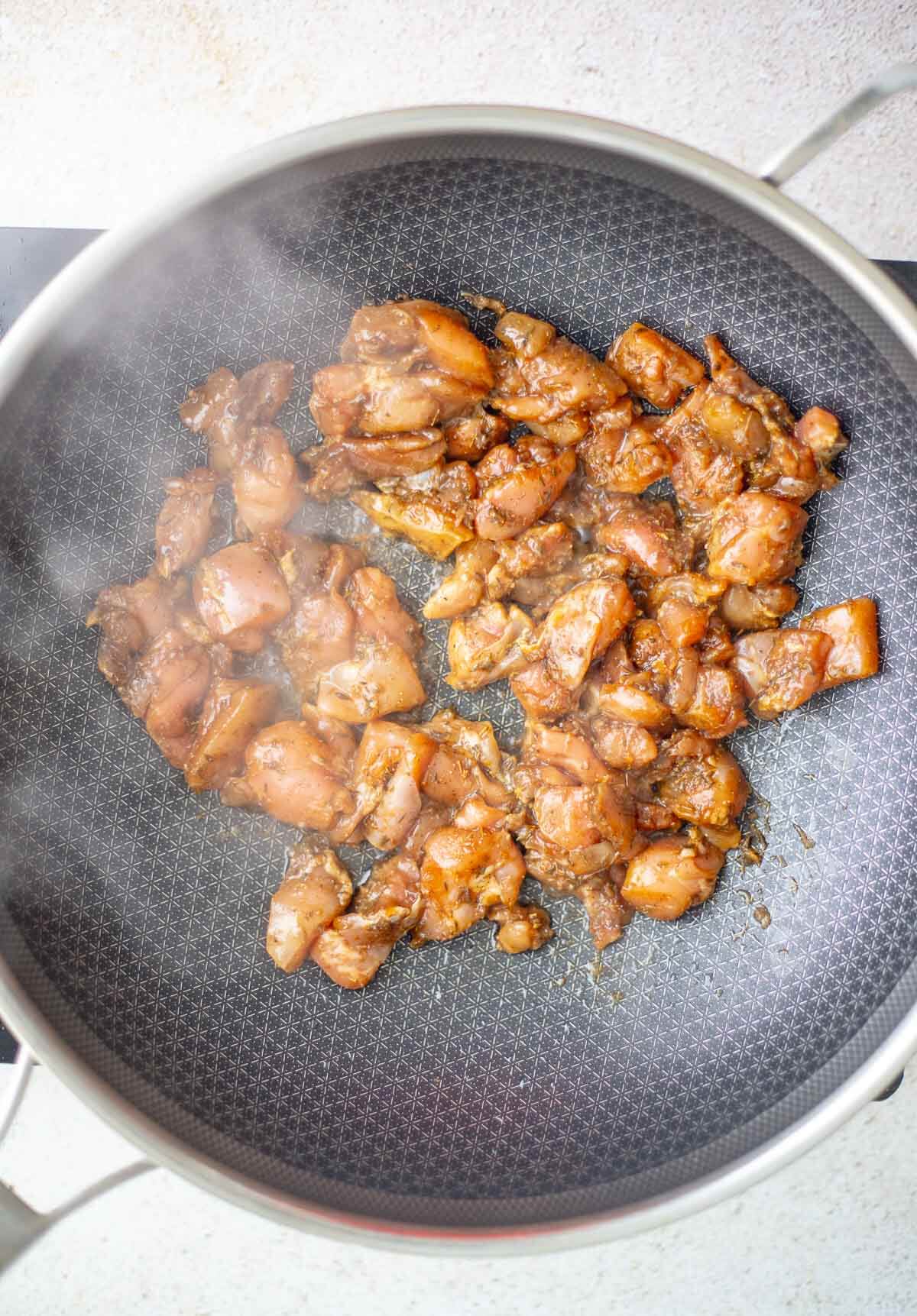 Seasoned chicken cooking in a pan for Caribbean chow mein