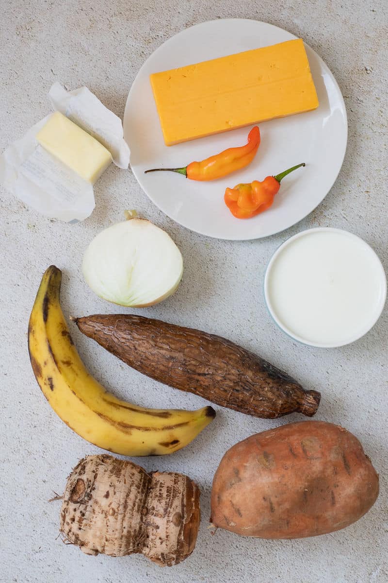 ingredients for ground provision pie including cassava, plantain, dasheen, sweet potato, cheese and milk