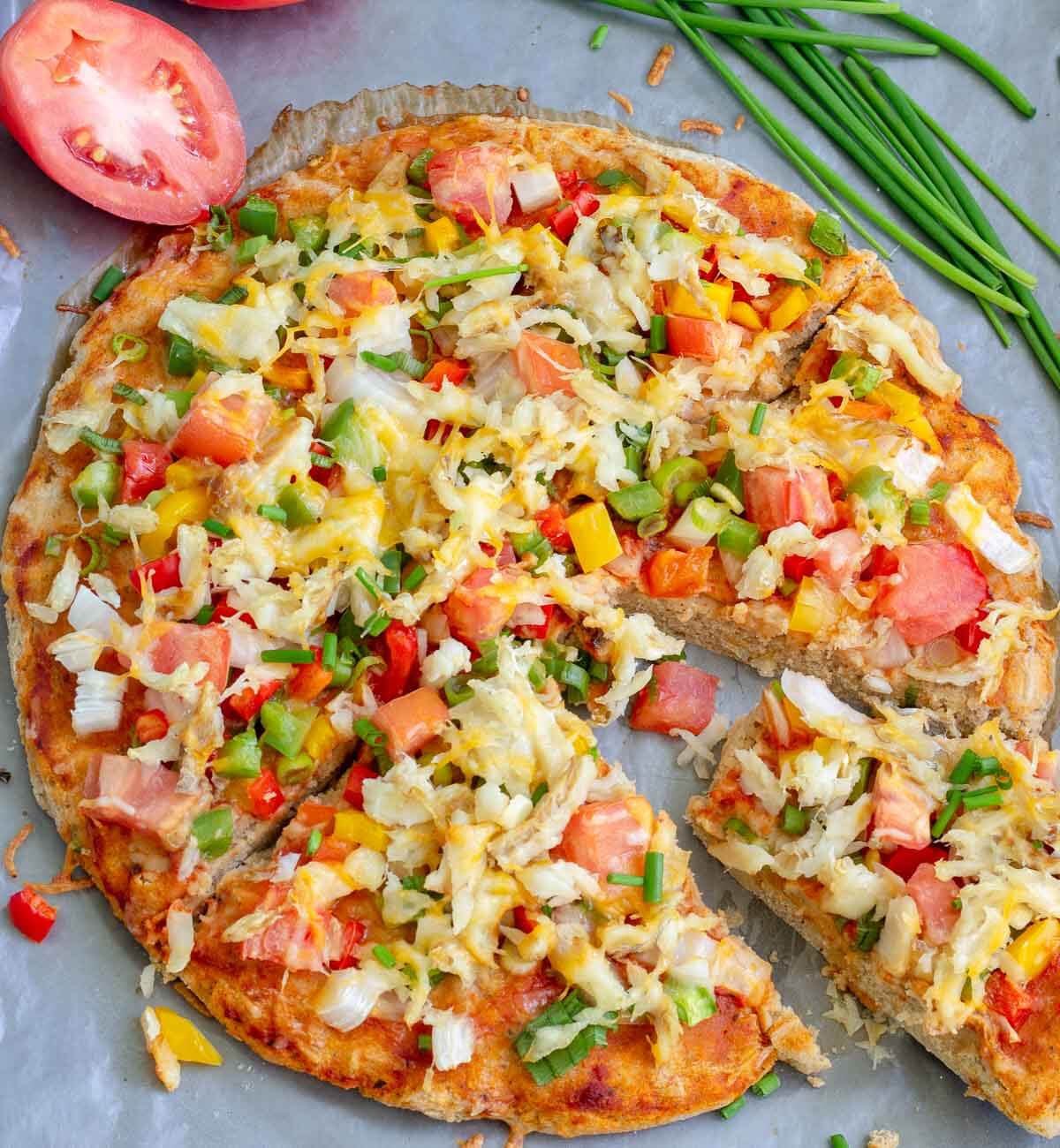 Caribbean saltfish pizza with a coconut bake-inspired crust topped with saltfish, peppers, tomatoes, onions, and cheese.