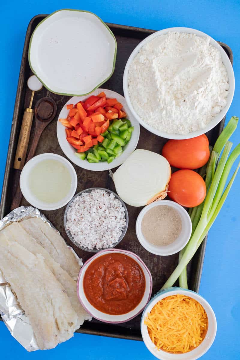 Ingredients including saltfish, coconut milk, vegetables, cheese, and flour.