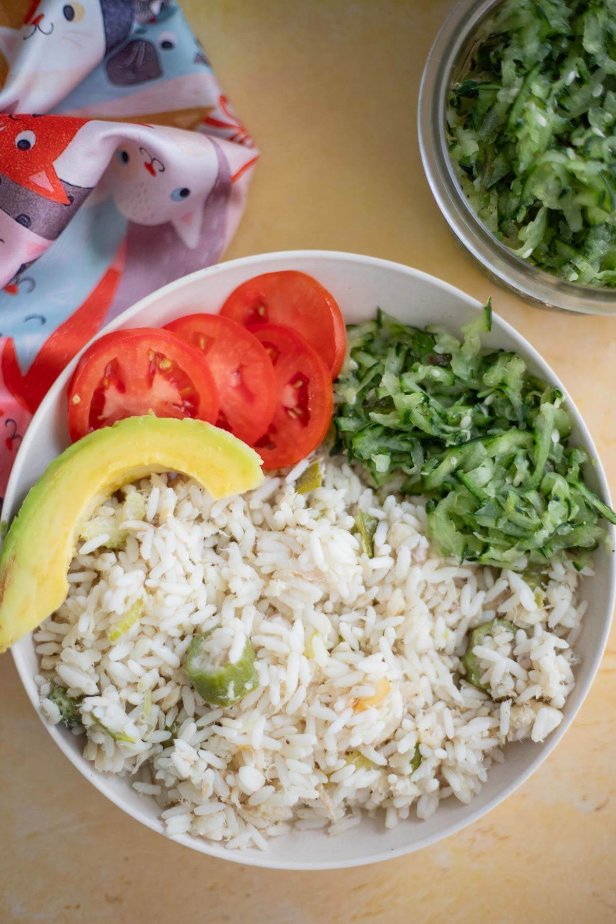 A simple one pot cook up dish of rice, saltfish and okra cooked in coconut milk. Ready to eat in 30 minutes in the instant pot. Bowl of saltfish and rice cook-up with cucumber salad and avocado.