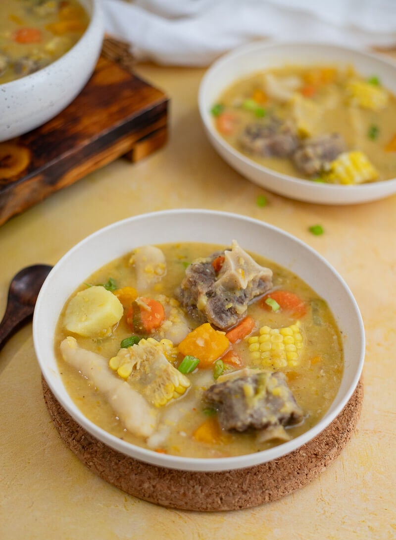 Bowl of Caribbean oxtail soup with dumplings, corn, pumpkin, and tender oxtail.