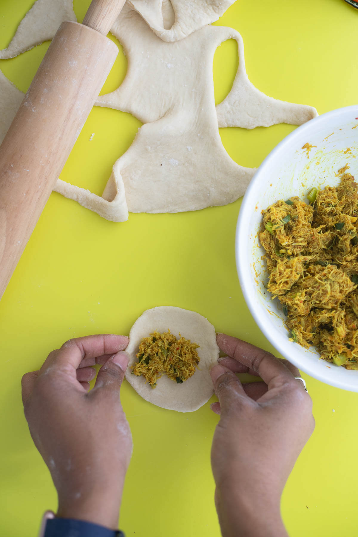 Two hands taking cooked curry crab and folding the dumplings closed.