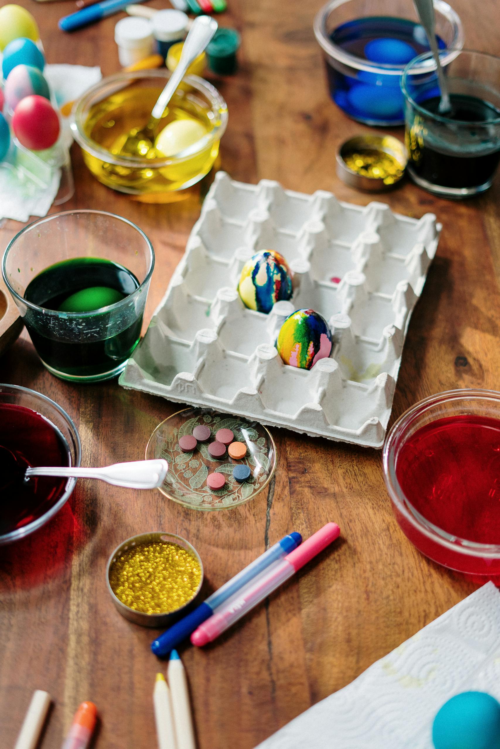 A vibrant arrangement of Easter eggs being decorated with paints and glitters, showcasing creativity.