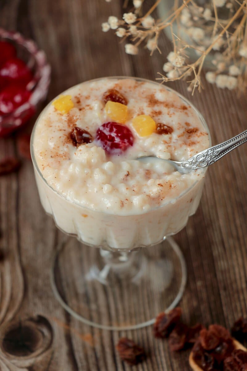 A scoop of rice pudding with toppings on fruit and dusted cinnamon.