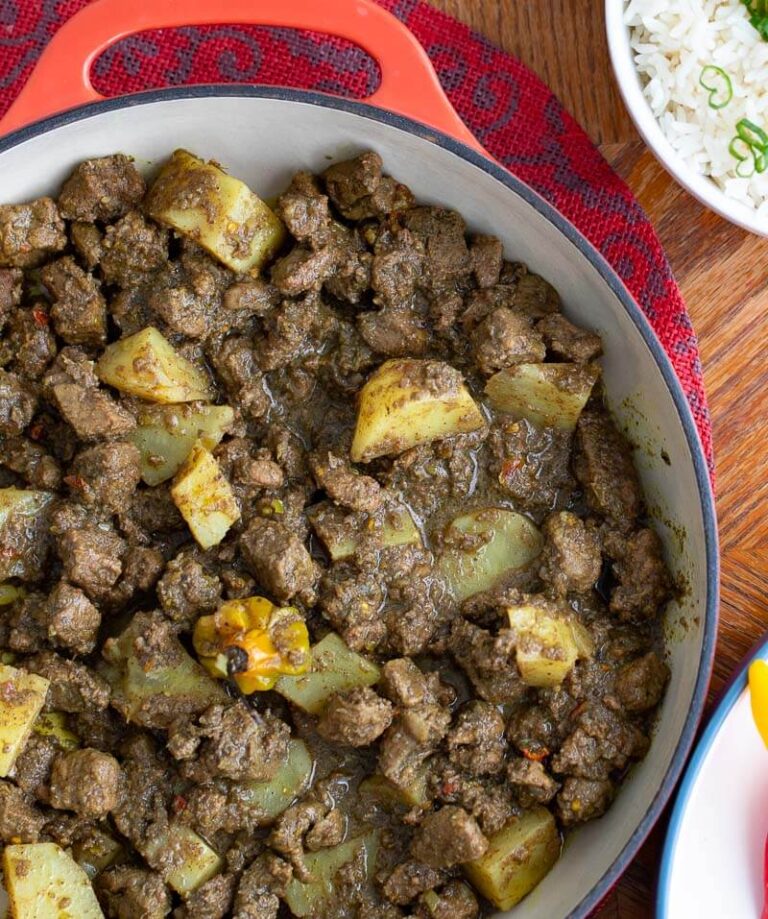 Close up of an orange pot of lamb curry with potatoes.