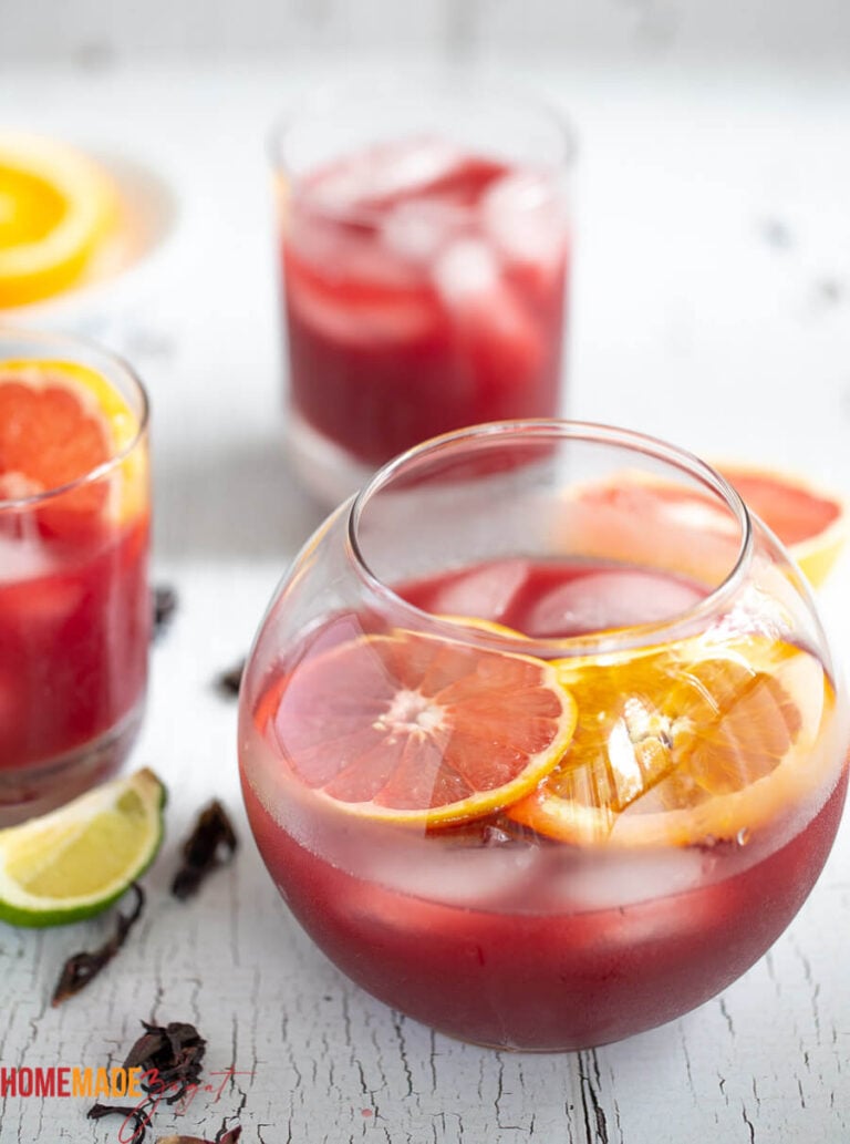 In this picture we have a mini punch bowl of sorrel rum punch with orange slices  and a peel of lime on the side.