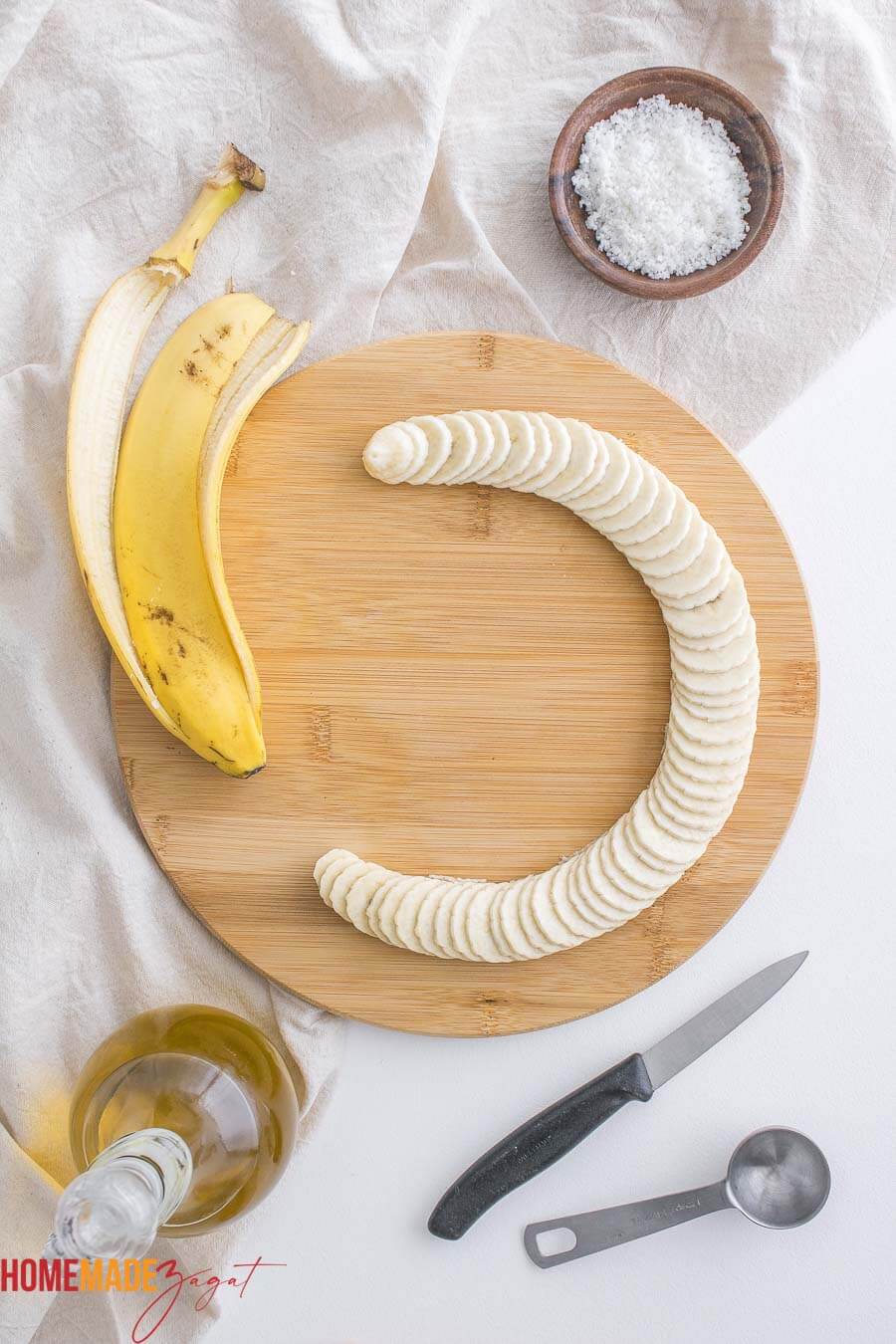 thinly sliced bananas on a cutting board with a white napkin..