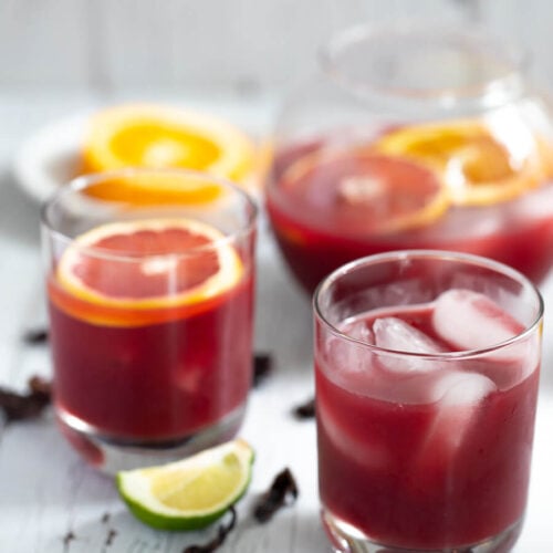 Glasses of rum punch with some sorrel flowers and a lime peel