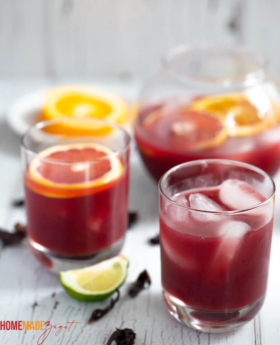 Glasses of rum punch with some sorrel flowers and a lime peel