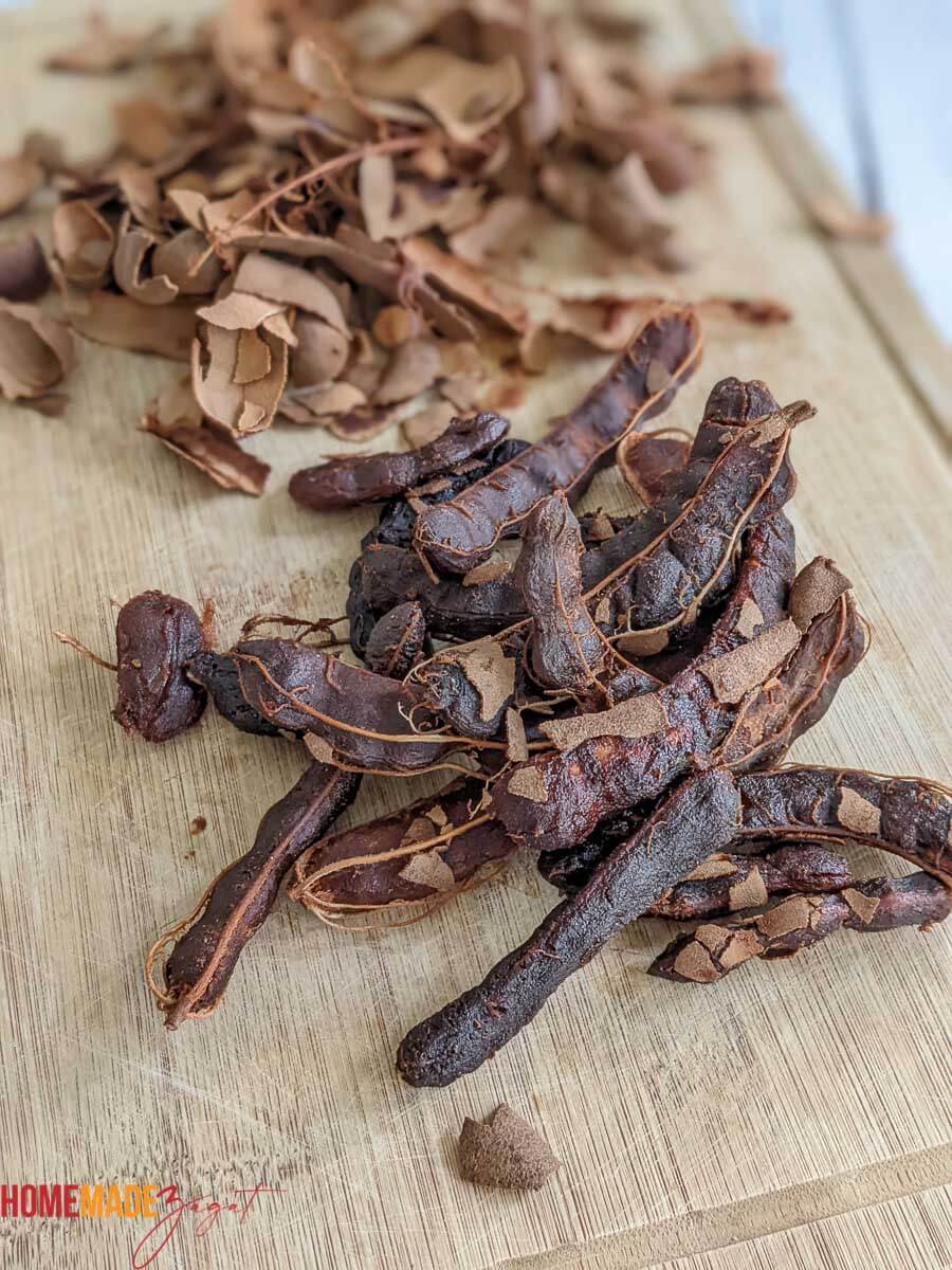 In this picture is some tamarind pods, shelled on a cutting board