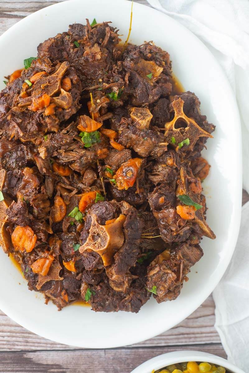 An overhead shot of a large plate of oxtail stew on a white plate.