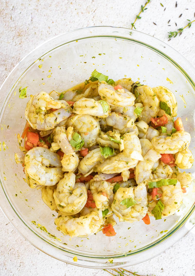 A picture of a bowl of seasoned shrimp sitting waiting to be cooked.