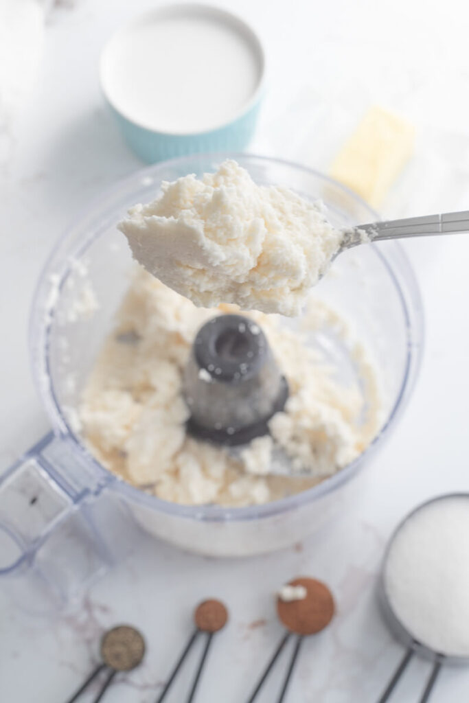 Finely ground cassava in a processor with a spoon showing the coarse.