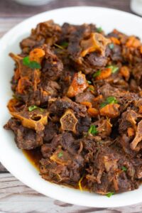 Straight on picture of a large plate of oxtail stew trini style