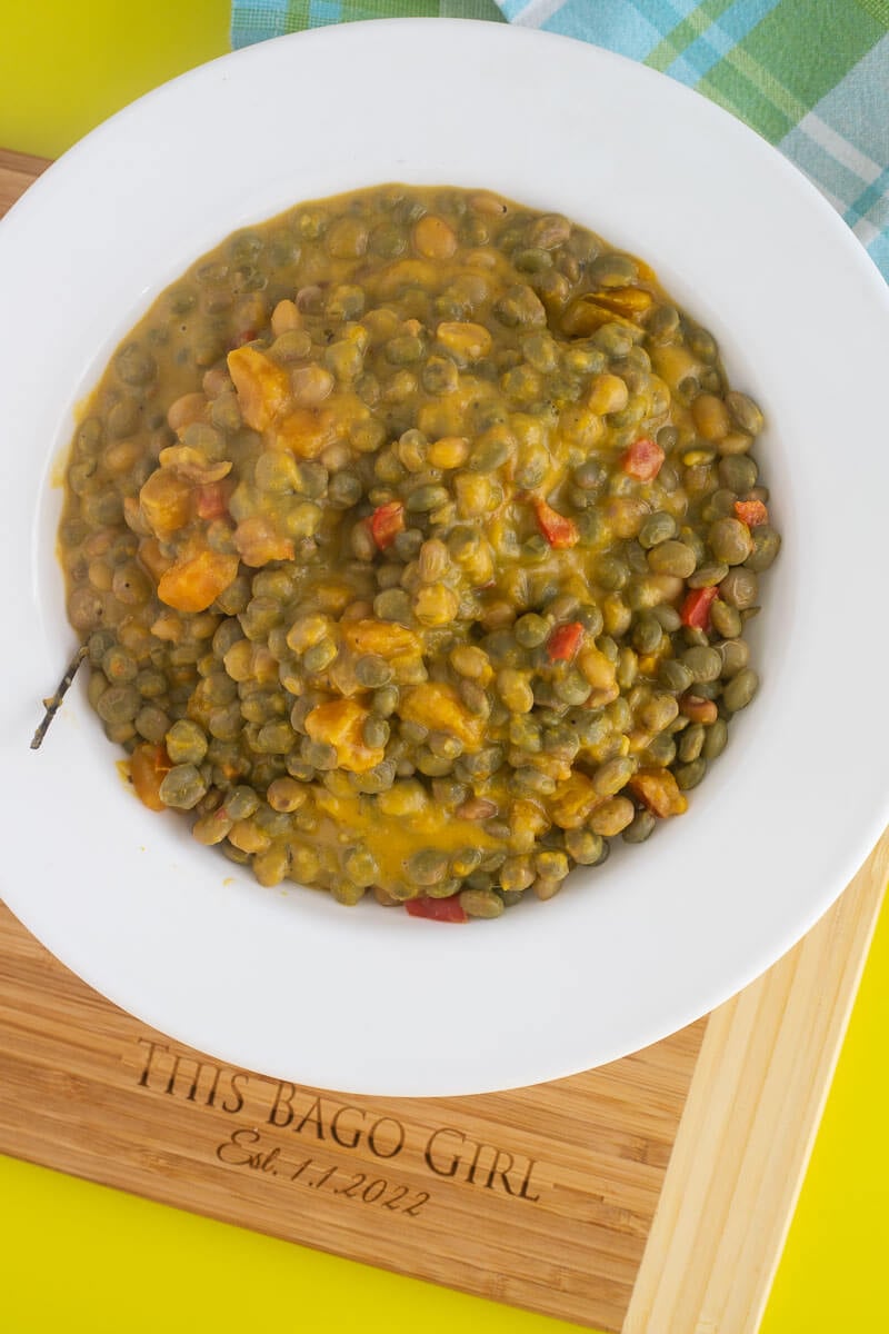 A bowl full of cooked stewed pigeon peas with pumpkin and thyme.