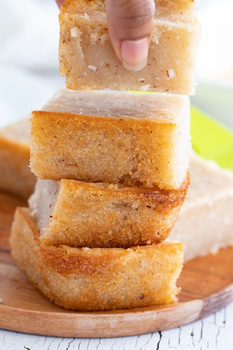 Stack of freshly baked cassava pone slices – gooey center with golden edges.