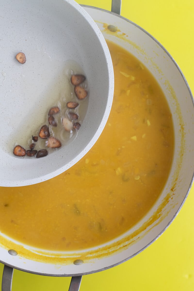 A pot of oil and burnt garlic being added too the cooked down split peas just before serving.