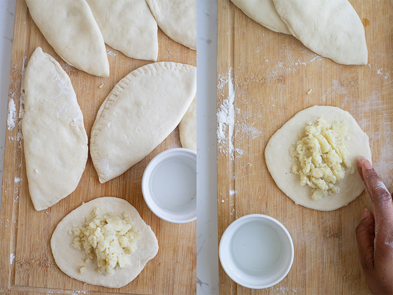 Aloo pies on a wooden cutting board showing how to put filling and how to dampen the edges.
