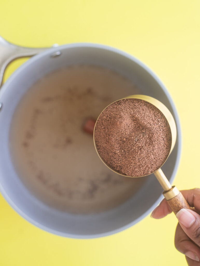 Overhead view of grated raw cacao chocolate being added to boiling water.