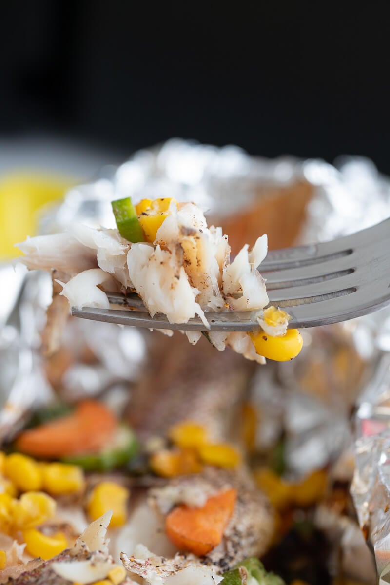 Crumbled fish on a fork with filling hovering over the whole fish.