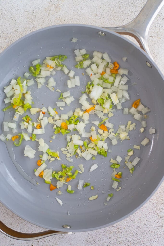 Aromatics frying up in oil in a frying pan.