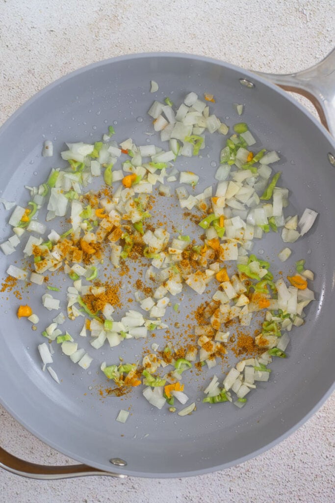 Curry powder on top of aromatics in a frying pan.
