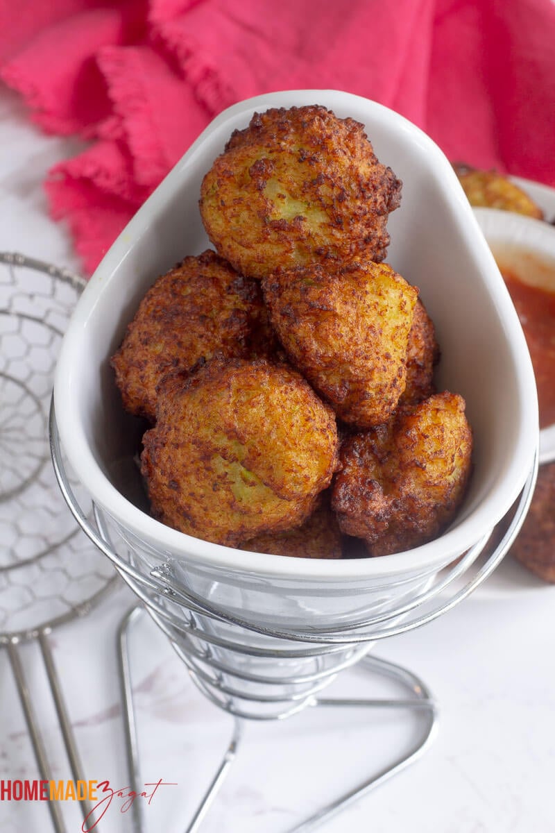 Bunches of golden fried conch fritters in a white dish ready to be served.