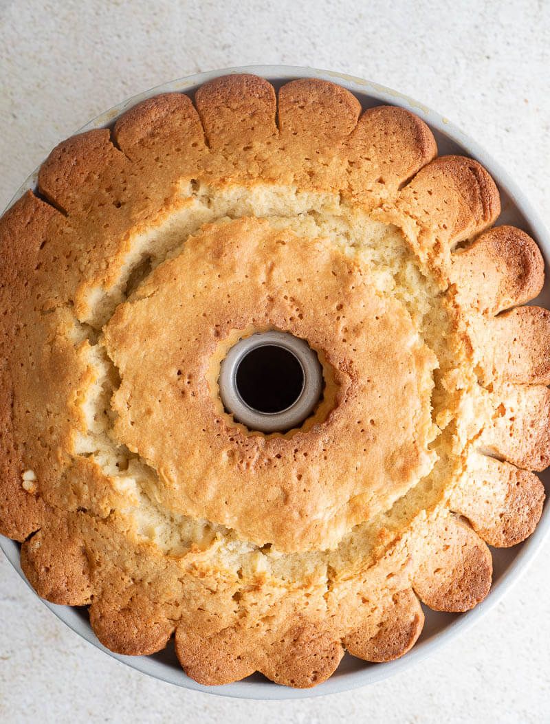 Crust of baked ponche de creme cake in a bundt pan on a creme backdrop.