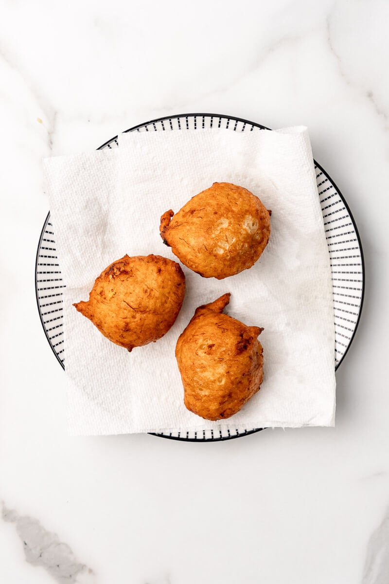 Fried banana fritters resting on paper towels to remove excess oil.