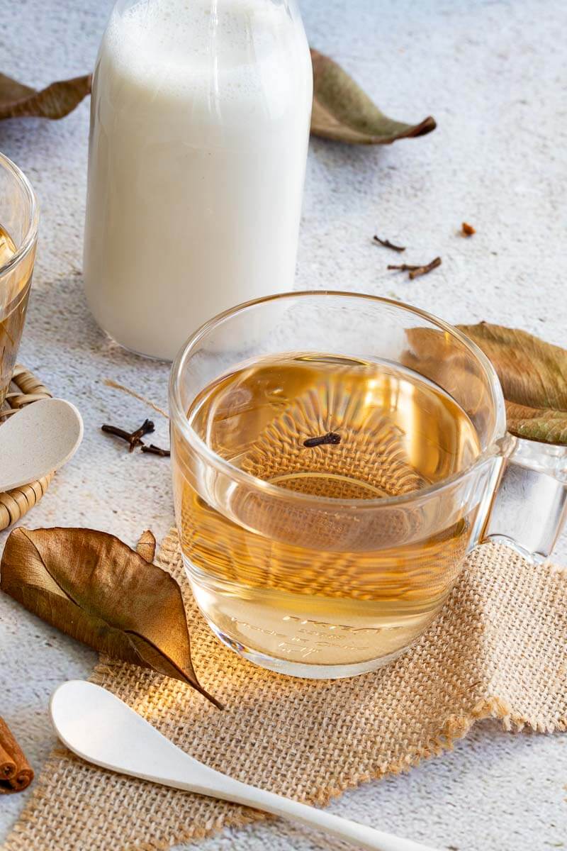 seeped bay leaf tea in a cup with a jug of milk in the background.