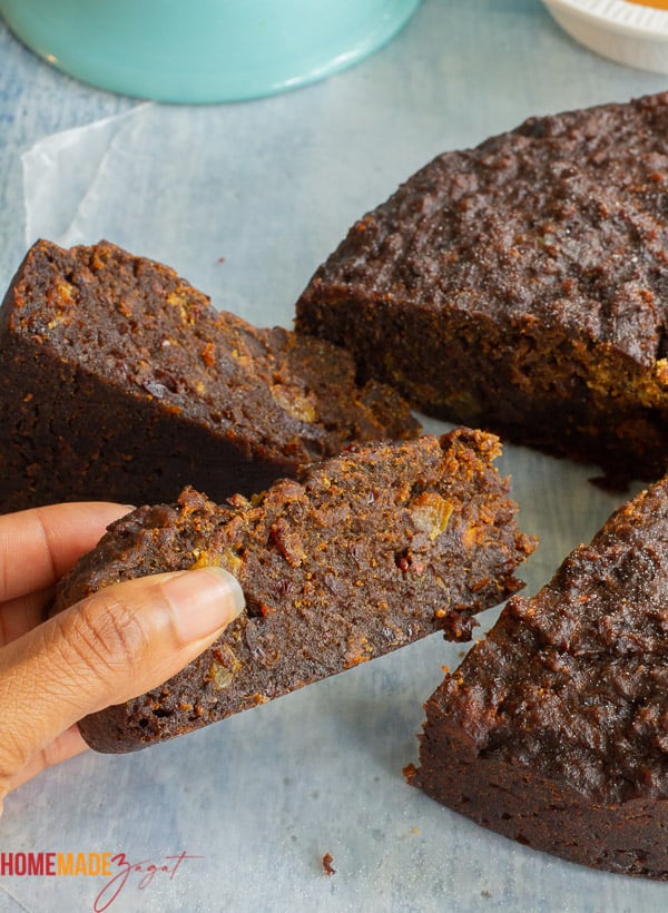 A hand holding a slice of the cake to see side view
